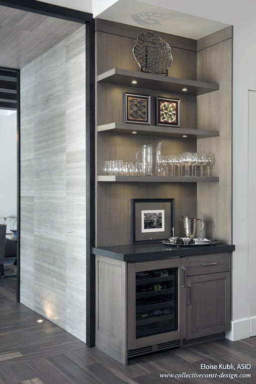 This wine storage and display area with a simple wood wrap leads into the living room beyond. Marble cladding lit from the floor offers a dramatic transition from the kitchen to the living room. Cabinetry: KitchenWorks