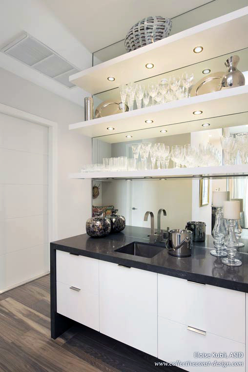 The white lacquer wet bar is located between the kitchen and dining room. A Pietra Grey Cesarstone&reg; counter top with a one sided waterfall and floating shelves  co-ordinates with the kitchen island. Cabinetry: KitchenWorks