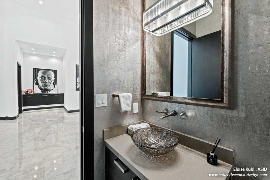 Sophisticated mirror and vessel sink with metallic wall covering in powder bath of custom home.