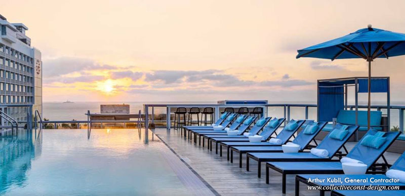 Full renovation of the rooftop pool deck, including faux grey wood porcelain tile, LED bollard lighting, and stainless steel floor drains.