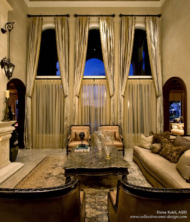 Floor-to-ceiling draperies create soft, elegant columns. Contrasting shapes add drama to the achitectural beauty of the arched window in this living space.(Courtesy of Collective Construction & Design)