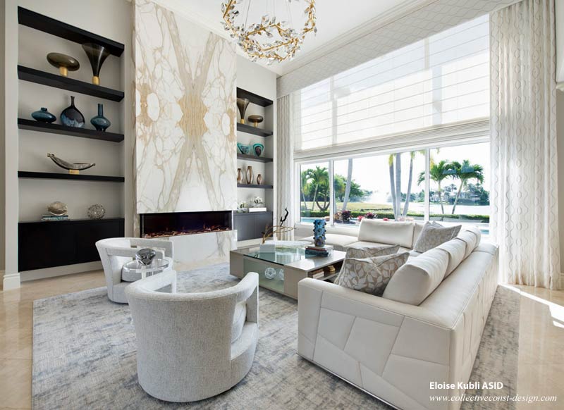 A living room with custom designed soaring 18-foot high architectural wall, fireplace, and surrounding millwork.