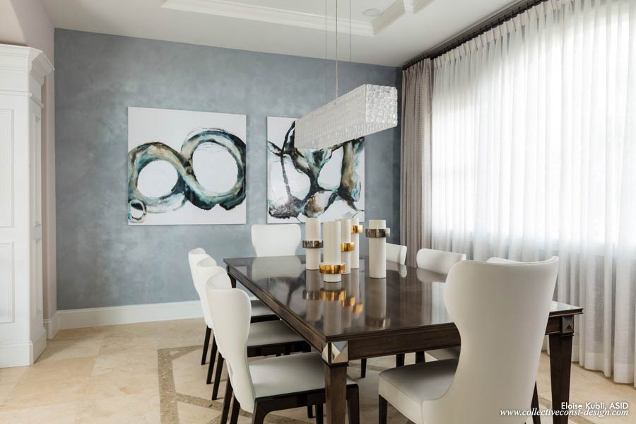 Sheers diffuse the neighboring view and are anchored by grey linen embroidered  panels. White leather chairs surround the charcoal and polished nickel dining table.