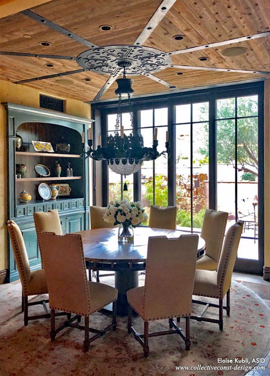 Breakfast room with round table, built-in dark wood shelves, wrought iron chandelier, wood floors, walls, and ceiling.